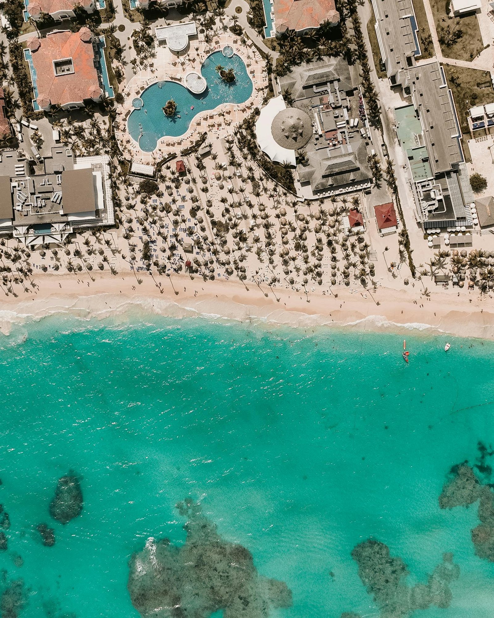 Stunning aerial shot of a beach resort with turquoise waters and lush palm trees.