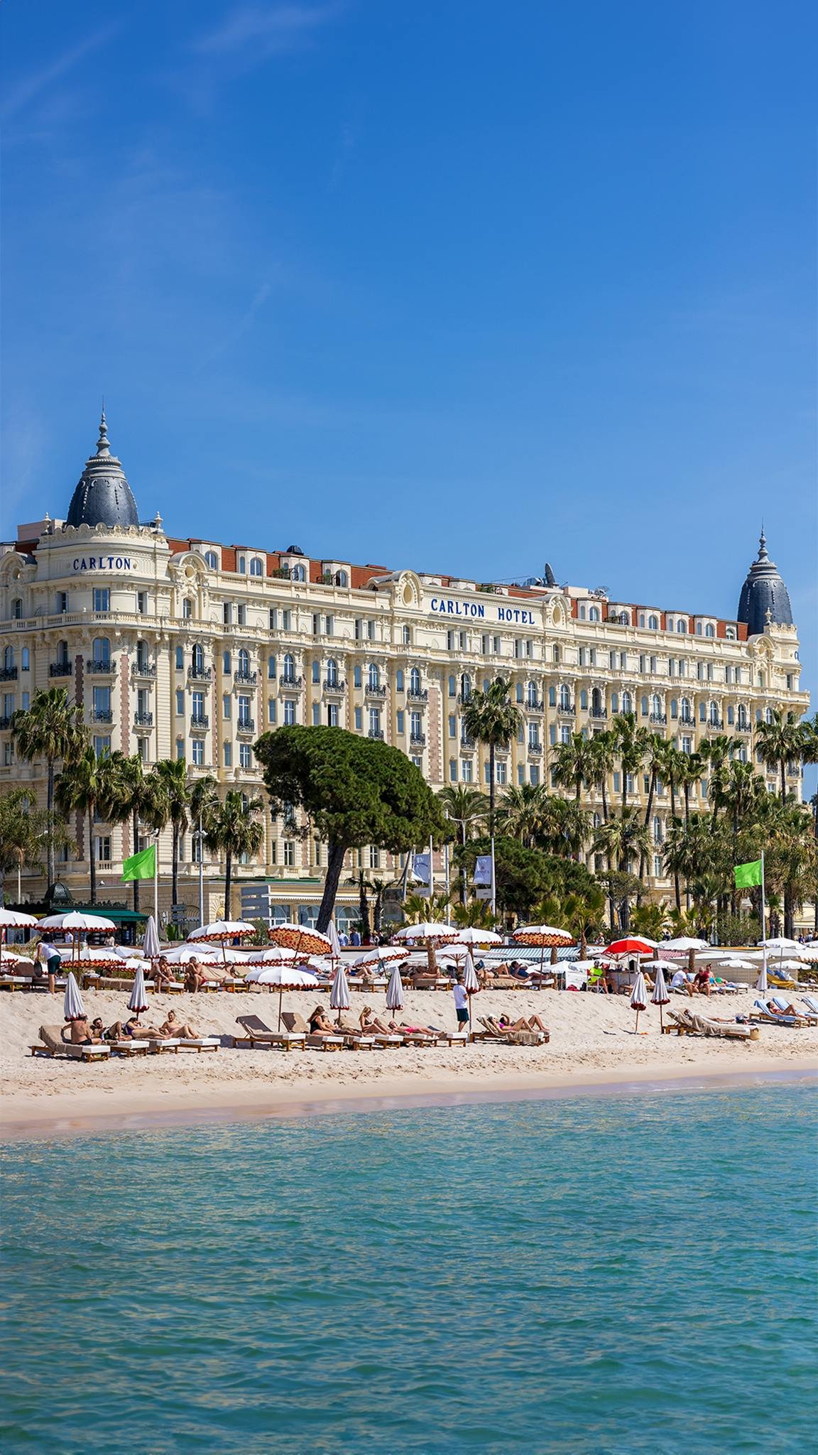 Sunny day at Carlton Hotel, Cannes with beachgoers enjoying the French Riviera.